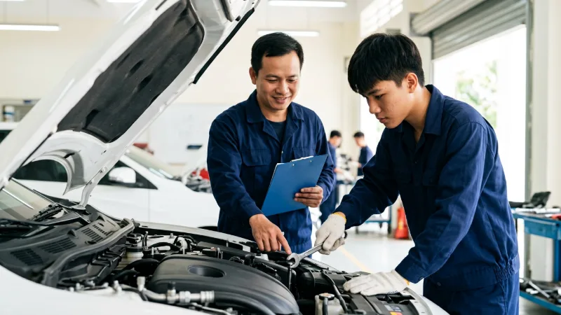 Giảng viên hướng dẫn sinh viên cao đẳng thực hành siết ốc trong khoang động cơ ô tô